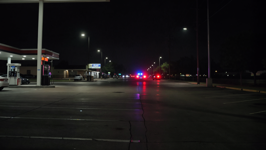 Night scene of a gas station parking lot in Humble Texas with distant cruiser lights