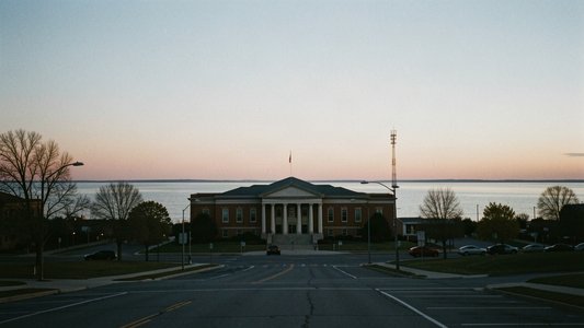 Muskegon County courthouse at dusk seen from a distance with a lone radio tower on the horizon