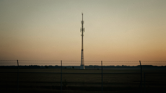 Radio transmission tower on a flat midwestern landscape at dusk with antennas against an amber sky